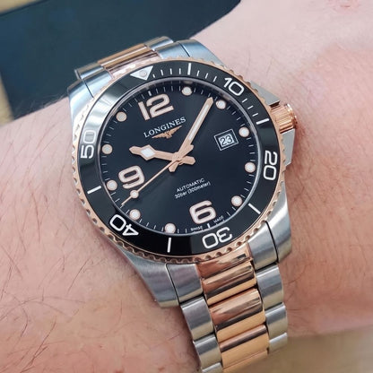 Longines HydroConquest oro rosa e acciaio indossato al polso, foto lifestyle primo piano quadrante nero e bracciale bicolore